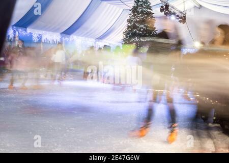 Malaga, Spanien - 08. Dezember 2017. Viele Menschen Schlittschuh auf große Eisbahn in der Winternacht, Bewegungsunschärfe Stockfoto