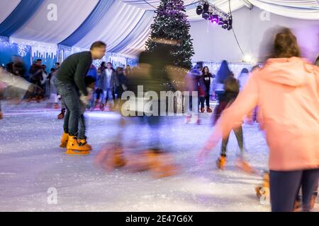 Malaga, Spanien - 08. Dezember 2017. Viele Menschen Schlittschuh auf große Eisbahn in der Winternacht, Bewegungsunschärfe Stockfoto