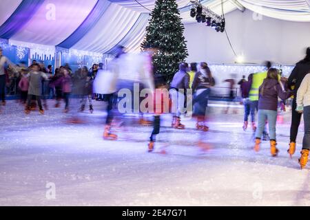 Malaga, Spanien - 08. Dezember 2017. Viele Menschen Schlittschuh auf große Eisbahn in der Winternacht, Bewegungsunschärfe Stockfoto