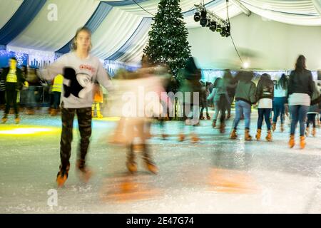 Malaga, Spanien - 08. Dezember 2017. Viele Menschen Schlittschuh auf große Eisbahn in der Winternacht, Bewegungsunschärfe Stockfoto