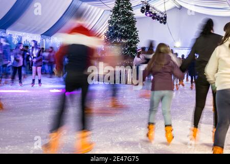 Malaga, Spanien - 08. Dezember 2017. Viele Menschen Schlittschuh auf große Eisbahn in der Winternacht, Bewegungsunschärfe Stockfoto