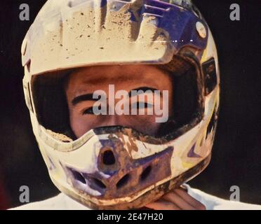 FRESNO, USA - Jan 06, 2021: Ein Retro-Foto aus der Nähe eines jungen Mannes, der seinen Motorradhelm trägt und die Sonne auf seinem Gesicht scheint Stockfoto