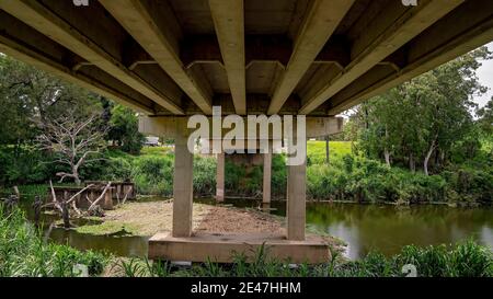 Die Unterseite einer Betonbrücke über einen Bach Stockfoto