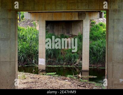 Die Unterseite einer Betonbrücke über einen Bach Stockfoto