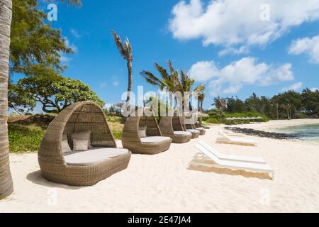 Sonnenliegen, Schoten, Stühle, aus gewebtem Rohr oder Material in einer Reihe an einem weißen Sandstrand auf der tropischen Insel Mauritius ohne Menschen Stockfoto