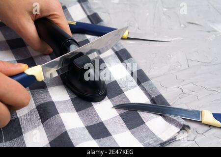 Der Mensch schärft Küchenmesser von Hand. Messer schärfen. Das Konzept der Pflege der Messerschärfe. Stockfoto