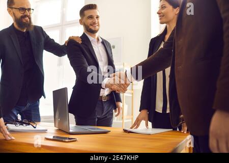 Lächelnde junge Geschäftspartner, die nach erfolgreichen Verhandlungen die Hände schütteln Büro Stockfoto