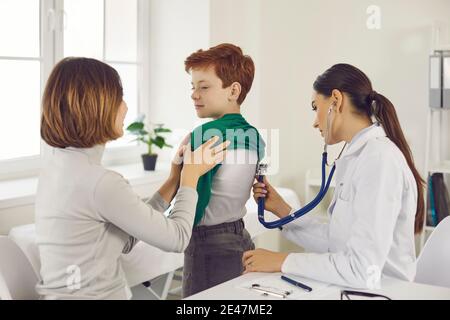 Frau Arzt Kinderarzt Untersuchung kleinen lächelnden Jungen mit Stethoskop Stockfoto