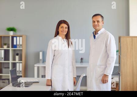 Glückliche Mitarbeiter im Gesundheitswesen in Laborkittel stehen zusammen in modernen Krankenhausbüro Stockfoto