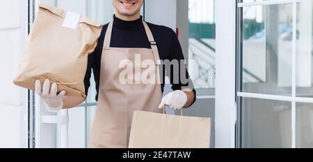 Verschiedene Papierbehälter für Essen zum Mitnehmen. Der Lieferer trägt Stockfoto