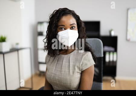 American African Frau im Büro Empfang in FFP2 Gesichtsmaske Stockfoto