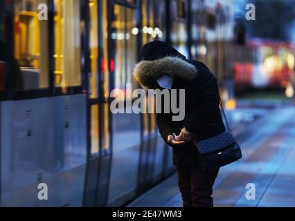 Köln, Deutschland. Januar 2021. Eine Frau desinfiziert ihre Hände an einer Straßenbahnhaltestelle. Die Kanzlerin und die Regierungschefs der Länder haben sich darauf geeinigt, die Sperre bis Februar 14 zu verlängern. Quelle: Oliver Berg/dpa/Alamy Live News Stockfoto