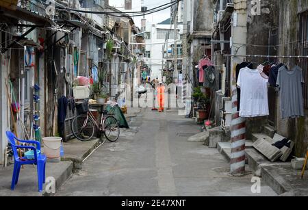 Straßenreiniger in der Innenstadt Yantian Bezirk Gemeinde, Shenzhen 2020. Im Gegensatz zu den modernen Gebäuden weiter westlich in der Stadt. Stockfoto