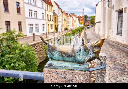 Schwein liegt auf dem Rücken als Bronzestatue auf der Kanalbrücke in der Stadt Wismar. Stockfoto