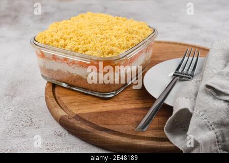 Geschichteter Salat mit Kartoffeln, Thunfisch, Karotten, Zwiebeln, Eiern und Mayonnaise. Traditioneller russischer Salat Mimosa mit Gemüse und Fisch. Stockfoto