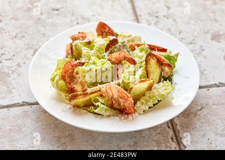 Portion cesar-Salat mit gegrillten Garnelen auf weißem Teller Stockfoto