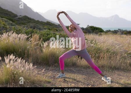 Fit african american Frau in Sportswear Stretching in hohen Gras Stockfoto
