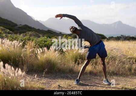 Fit afroamerikanischen Mann in Sportswear Stretching im hohen Gras Stockfoto