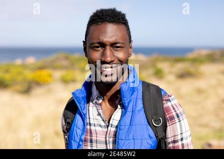 Porträt von fit afroamerikanischen Mann trägt Rucksack Wandern auf Küste Stockfoto