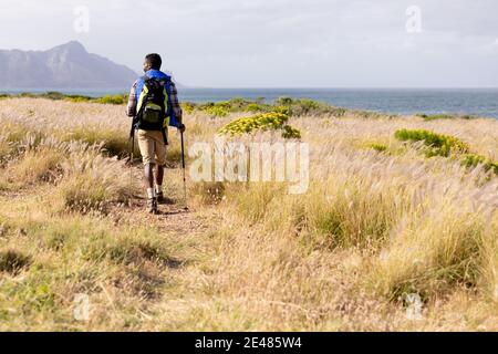 Fit afroamerikanischen Mann trägt Rucksack nordic Walking an der Küste Stockfoto