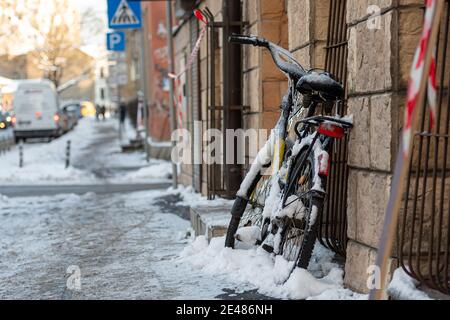 Ein Fahrrad mit Eis und Eiszapfen an der Wand bedeckt Des Gebäudes auf dem Bürgersteig Stockfoto