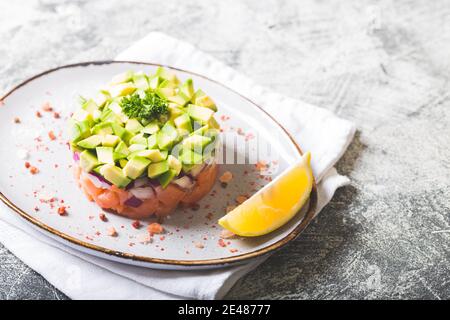 Salat aus rohem Lachs, Avocado und violetten Zwiebeln. Lachstartar Stockfoto