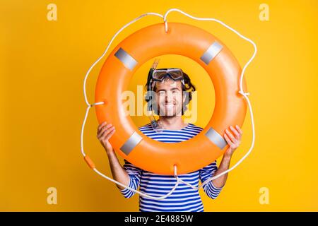 Foto von Kerl in Scuba Brillen halten Rettungsboje in der Nähe Gesicht tragen gestreiftes blaues Hemd isoliert auf gelbem Hintergrund Stockfoto