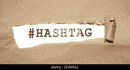 Das Wort Hashtag erscheint hinter zerrissenem Papier. Stockfoto