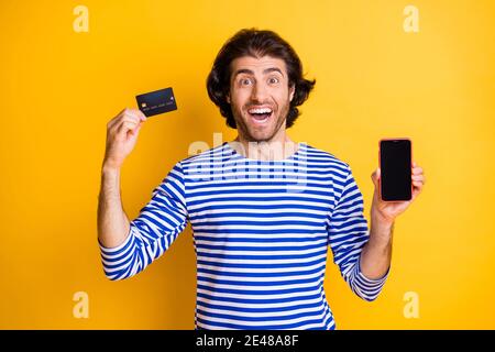 Foto von verrückt erstaunt mittleren östlichen Kerl halten Smartphone Kredit Karte tragen Gekittel isoliert auf gelbem Hintergrund Stockfoto