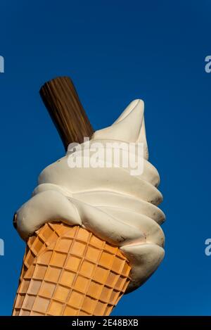 Großer Eiskegel mit Flockenwerbung an Southend am Meer an einem hellen Wintertag. Übergroße Eiscreme-Kornett-Schild in blauem Himmel. Anzeigen Stockfoto