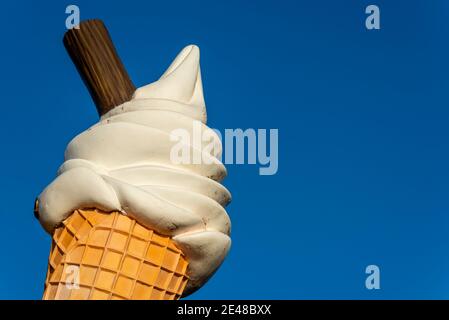 Großer Eiskegel mit Flockenwerbung an Southend am Meer an einem hellen Wintertag. Übergroße Eiscreme-Kornett-Schild in blauem Himmel. Anzeigen Stockfoto