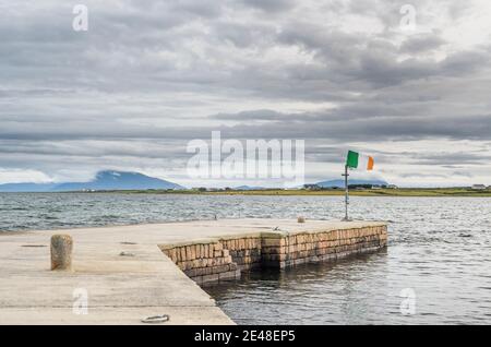 Der Pier in der Stadt Belmullet, County Mayo, Irland, mit irischer Flagge (tricolor) Stockfoto