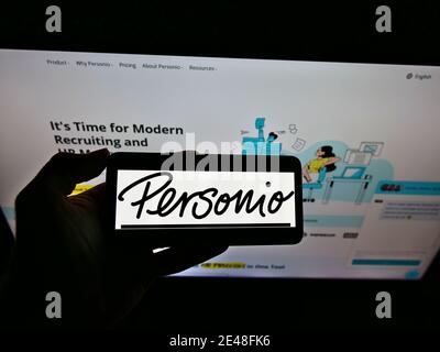 Person, die Smartphone mit Logo des deutschen Personalsoftware-Entwicklers Personio GmbH auf dem Display vor der Website hält. Konzentrieren Sie sich auf das Mobiltelefon. Stockfoto
