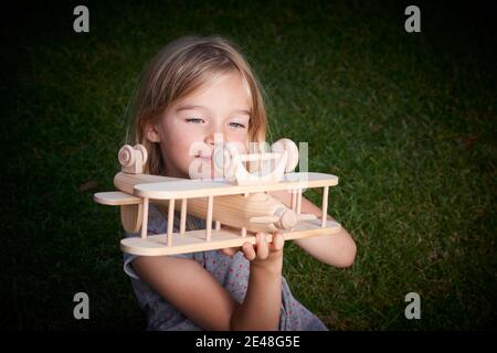 Träume vom Flug! Kind spielt mit Spielzeug Flugzeug. Glückliches Kind träumt von Reisen und Spielen mit einem Flugzeug im Freien im Sommer Stockfoto