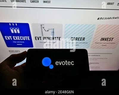 Person mit Smartphone mit Firmenlogo des deutschen Biotechnologieunternehmens Evotec AG auf dem Display vor der Website. Konzentrieren Sie sich auf den Bildschirm des Mobiltelefons. Stockfoto