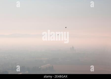 Panoramablick Nebel italienisches Tal in Assisi - Umbrien während Sonnenuntergang mit Bergen und Kirche oder Basilika Santa maria Degli angeli im Hintergrund Stockfoto