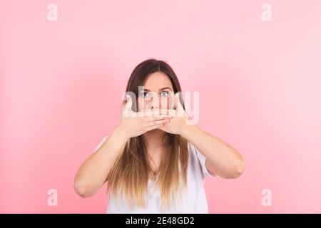 Junge Frau bedeckt ihren Mund mit beiden Händen. Ausdruck der Stille Stockfoto