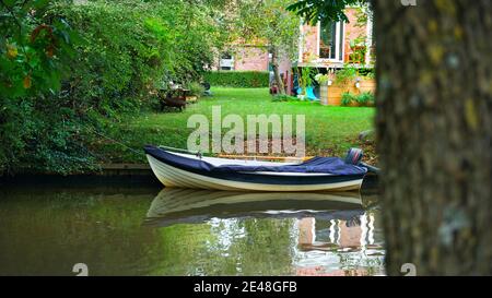 Typisches Motorboot im Kanal direkt vor einem Haus, Emden Deutschland Stockfoto