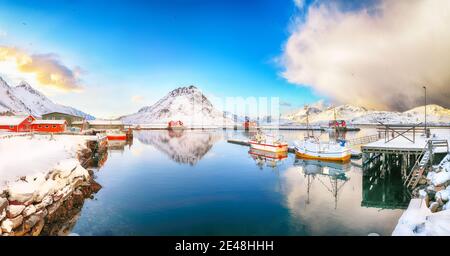 Erstaunlicher Wintersonnenaufgang über Ramberg Dorf und Hafen. Festgemacht Fischerschiffe im Hafen. Lage: Ramberg, Flakstadoya Insel, Lofoten; Norwegen, Europa Stockfoto