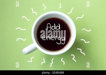 Schwarzer Kaffee in einer weißen Tasse isoliert auf einem hellgrünen Hintergrund. Inschrift Energie hinzufügen. Draufsicht Stockfoto