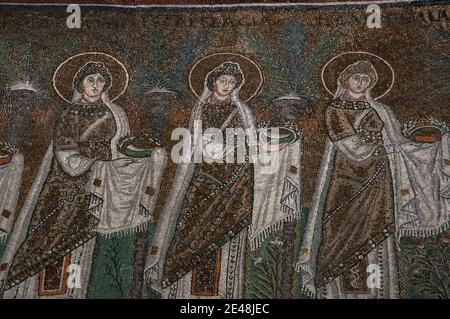 Drei von 22 mit Juwelen geschmückten und prächtig gekleideten weiblichen christlichen Heiligen, die in einer Prozession laufen. Detail des byzantinischen Mosaiks in der Basilica di Sant’Apollinare Nuovo in Ravenna, Emilia-Romagna, Italien. Das Mosaik entstand in den 500er Jahren n. Chr., wenige Jahre nachdem Ravenna von den Ostgoten erobert wurde. Stockfoto