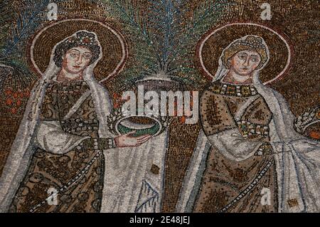 Zwei von 22 mit Juwelen geschmückten und prächtig gekleideten weiblichen christlichen Heiligen, die in einer Prozession laufen. Detail des byzantinischen Mosaiks in der Basilica di Sant’Apollinare Nuovo in Ravenna, Emilia-Romagna, Italien. Das Mosaik entstand im 6. Jahrhundert n. Chr., wenige Jahre nachdem Ravenna vom byzantinischen Reich von den Ostgoten erobert wurde. Stockfoto