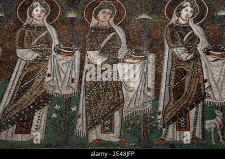 Drei von 22 mit Juwelen geschmückten und prächtig gekleideten weiblichen christlichen Heiligen, die in einer Prozession laufen. Detail des byzantinischen Mosaiks in der Basilica di Sant’Apollinare Nuovo in Ravenna, Emilia-Romagna, Italien. Das Mosaik entstand in den 500er Jahren n. Chr., wenige Jahre nachdem Ravenna von den Ostgoten erobert wurde. Stockfoto