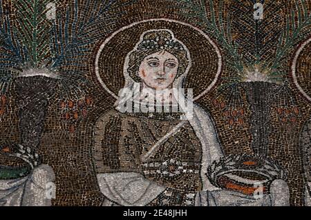 Eine von 22 prächtig gekleideten weiblichen christlichen Heiligen oder Jungfrau Märtyrern geht in einer Prozession. Detail aus dem byzantinischen Mosaik, das in den 500er Jahren n. Chr. in der Basilica di Sant’Apollinare Nuovo in Ravenna, Emilia-Romagna, Italien, geschaffen wurde. Stockfoto