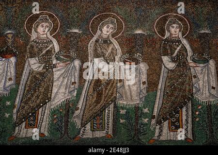 Drei von 22 mit Juwelen geschmückten und prächtig gekleideten weiblichen christlichen Heiligen, die in einer Prozession laufen. Detail des byzantinischen Mosaiks in der Basilica di Sant’Apollinare Nuovo in Ravenna, Emilia-Romagna, Italien. Das Mosaik entstand in den 500er Jahren n. Chr., wenige Jahre nachdem Ravenna von den Ostgoten erobert wurde. Stockfoto