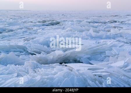 Viele Eisstücke bedeckt mit weißem Schnee auf einem wieder gefrorenen Gewässer. Winter in Osteuropa. Querformat. Horizontale Ausrichtung. Stockfoto