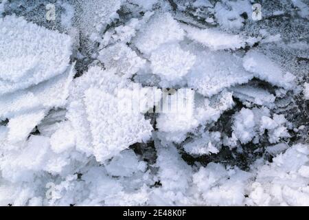 Eisstücke bedeckt mit Schnee auf einem wieder gefrorenen Gewässer. Winter in Osteuropa. Horizontale Ausrichtung. Stockfoto