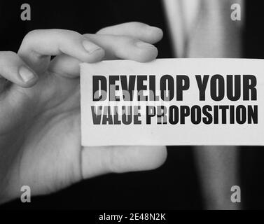 Geschäftsmann zeigt eine Karte mit Text ENTWICKELN SIE IHR WERTVERSPRECHEN. Management Business Achievements Motivationskonzept. Stockfoto