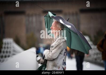 Mann stand auf Brücke großen zerbrochenen Regenschirm im Regen London City Centre Augen geschlossen genießen frische Luft Blick über Thames River obdachlos älteren Schloss Stockfoto