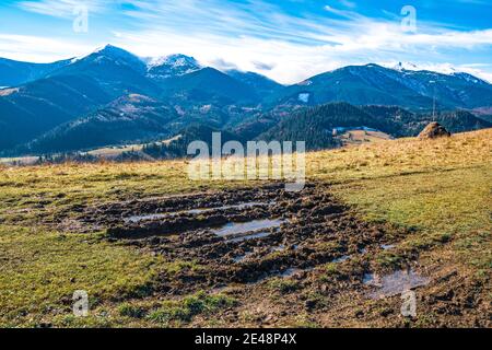 Eine riesige schlammige Pfütze mit ekelhaftendem Schlamm auf einem kleinen Weg in den Karpaten Berge vor der Kulisse der schönen Herbsthügel Stockfoto